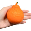 An orange tangerine-shaped squishy stress relief toy is held in a person's hand.