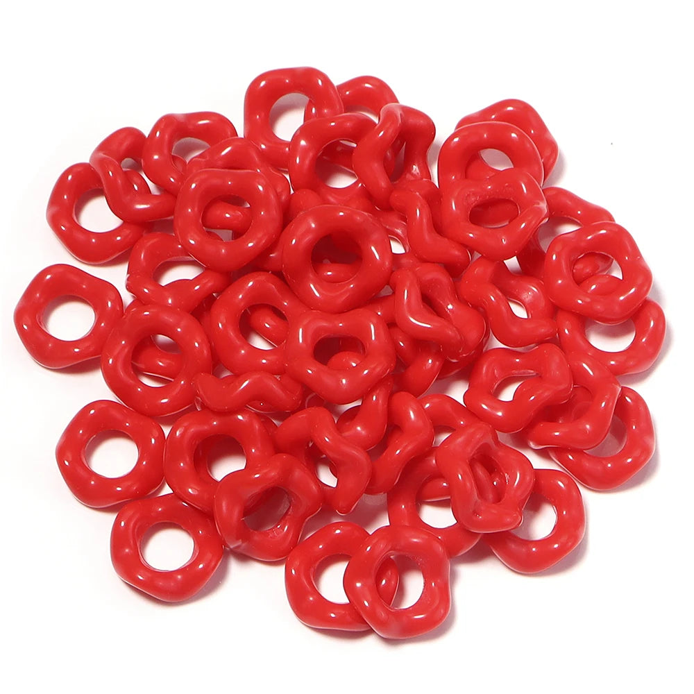 A pile of bright red acrylic doughnut spacer beads for jewelry making