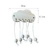A light wood cloud shaped DIY Montessori busy board with hanging sensory balls for toddlers.