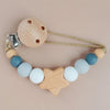 A wooden pacifier clip with silicone beads and a cord, featuring a star shape.