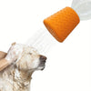An orange silicone pet shower head is spraying water onto a dog's face.