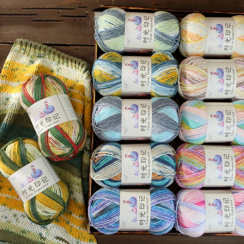 A box containing three spools of gradient acrylic yarn in various colors and shades for knitting and crochet.