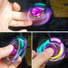 A hand spins a colorful metal fidget spinner, showing vibrant iridescent light and motion.