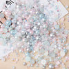 A pile of mixed resin rhinestone pearls with an AB finish in various shades of pink, blue, and silver for crafts and nail art