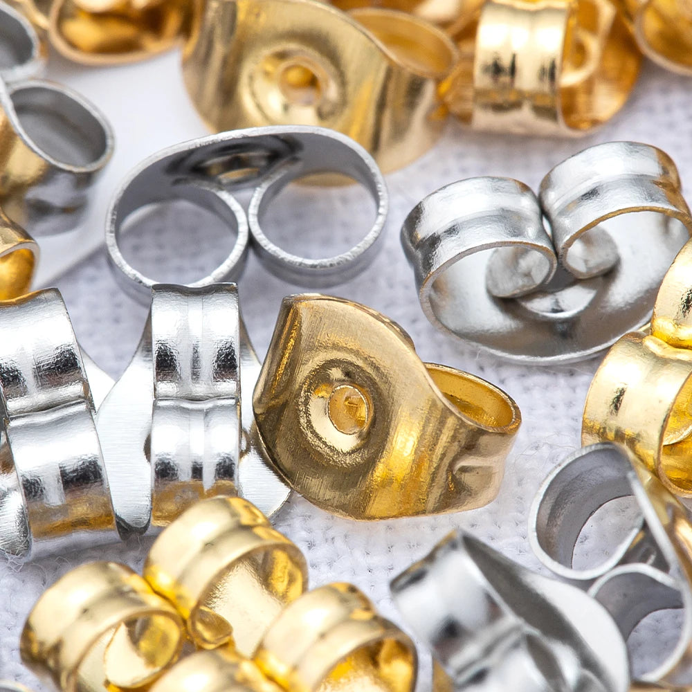 A close-up of various gold and silver stainless steel earring stud bases and backs for DIY jewelry making.