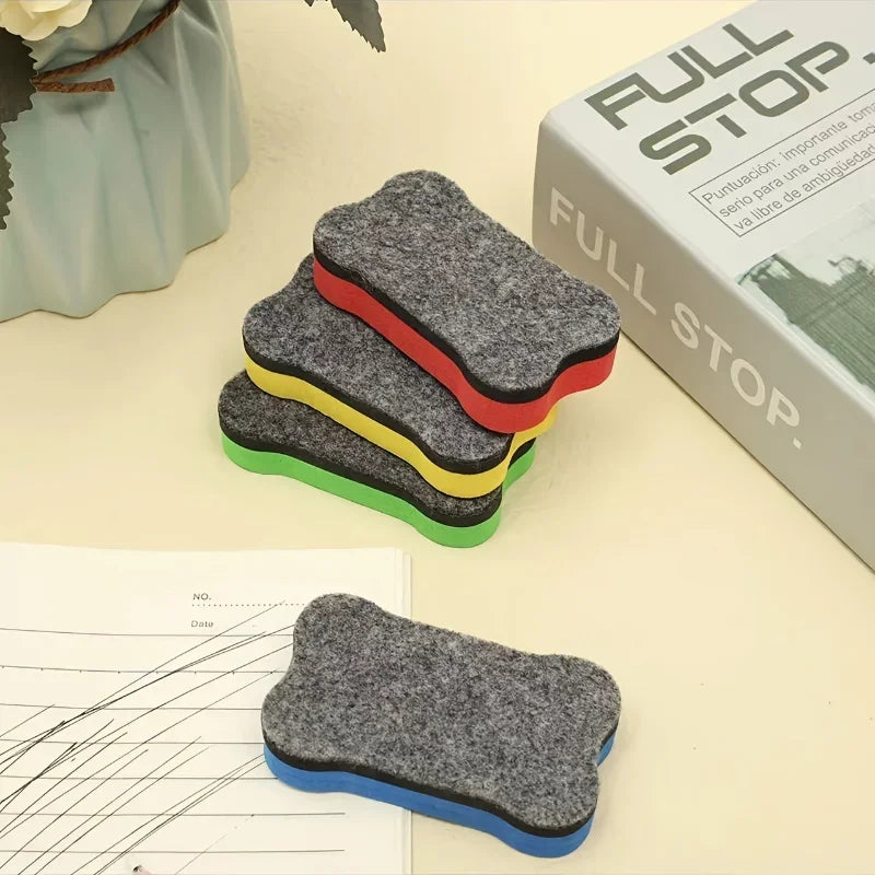 A stack of three colored magnetic dry erase erasers, including gray, red, and yellow, resting on a light surface.