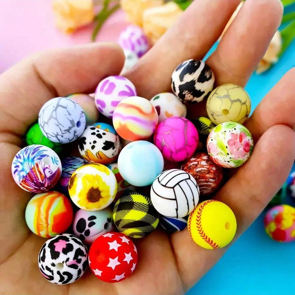 A hand holds a variety of colorful printed silicone beads for DIY jewelry making.