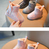 A pair of pink and purple fur-lined winter snow boots displayed on a light brown surface.