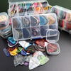 A variety pack of celluloid guitar picks in various colors and shapes is displayed alongside a clear storage box.