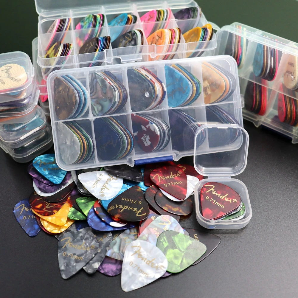 A variety pack of celluloid guitar picks in various colors and shapes is displayed alongside a clear storage box.