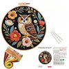 Embroidery kit featuring an owl and flower design on a wooden board with threads and tools.