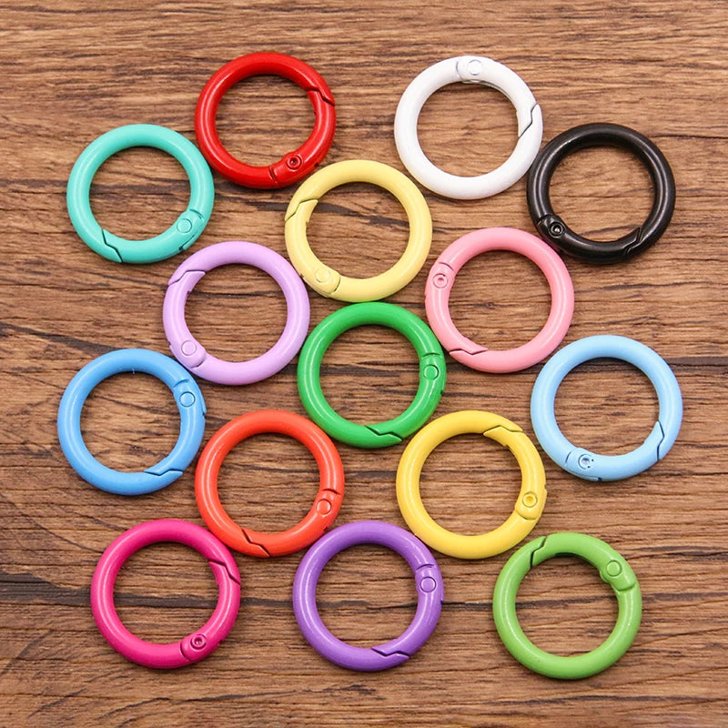 A collection of ten colorful metal O-ring spring clasps in various colors like red, white, black, green, and pink, arranged o