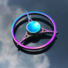 A colorful metal fidget spinner with a glowing blue center and purple accents, resting on a reflective surface.