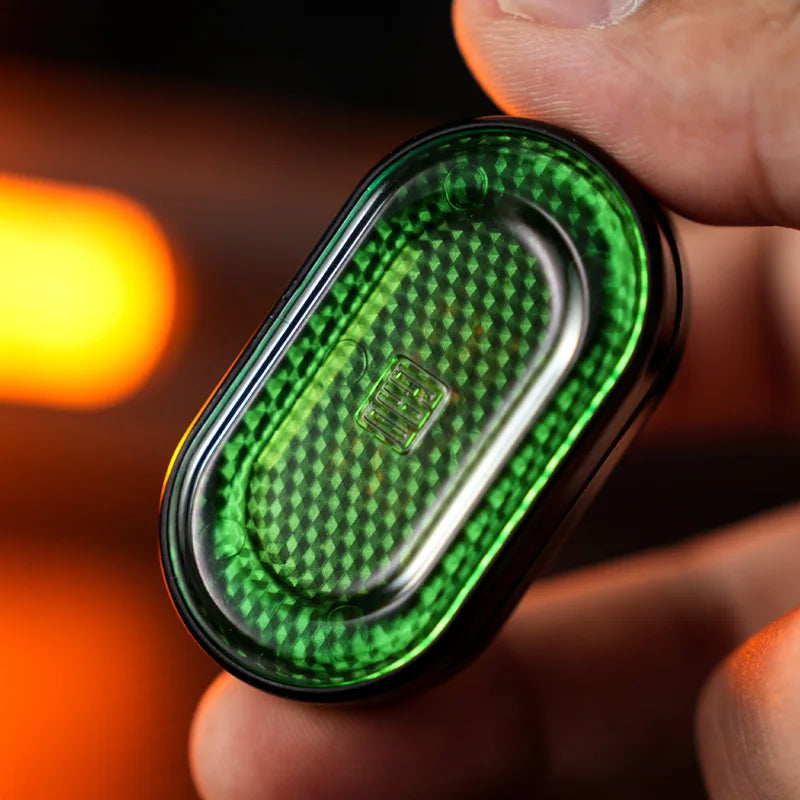 A hand holds a green metal mechanical fidget slider with a diamond pattern design.