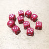 A collection of red dice scattered on a light wooden surface.
