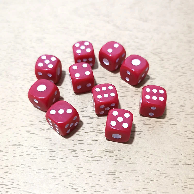 A collection of red dice scattered on a light wooden surface.