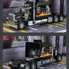 A black Peterbilt 389 diecast truck model with lights and sound displayed on a diorama.