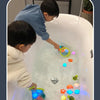 Two children play with glow-in-the-dark animal washing water toys in a bathtub.