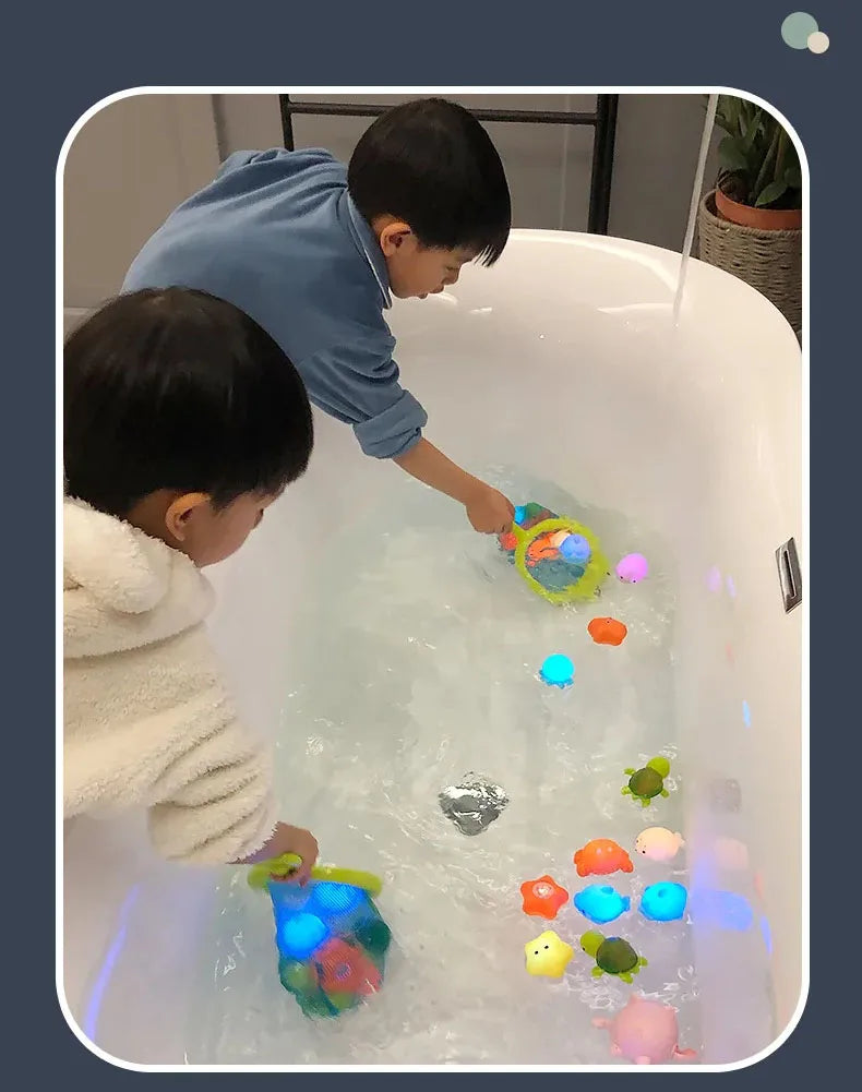 Two children play with glow-in-the-dark animal washing water toys in a bathtub.