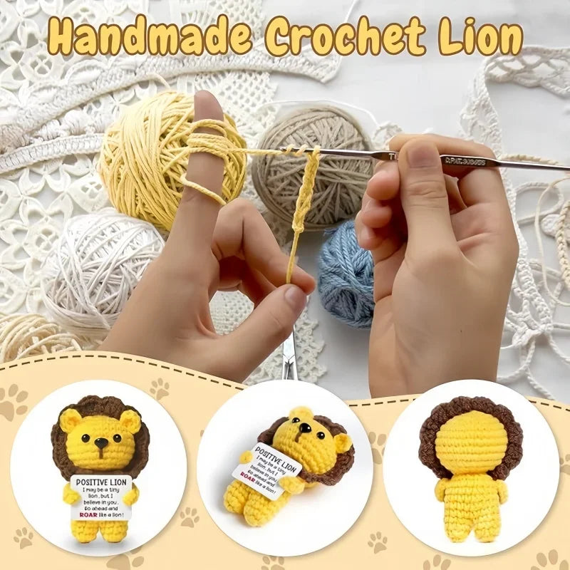 Hands are crocheting a yellow lion doll with a positive message card using yarn and a needle.