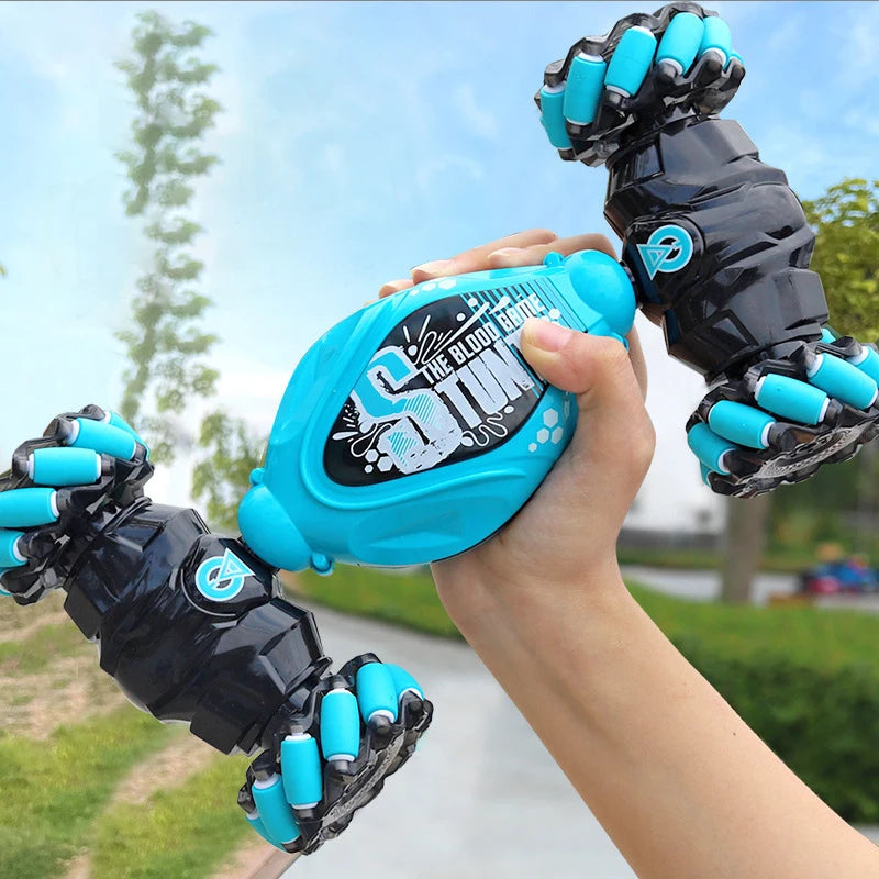 A hand holds a black RC stunt car with blue grips and LED lights, demonstrating gesture control.