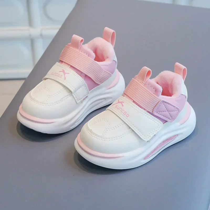 A pair of pink and white kids' everyday sneakers with soft pink lining and white soles resting on a gray surface.