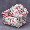 A miniature 1:12 scale sofa and pillow set for a dollhouse featuring a white fabric with pink floral patterns.
