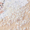 A scatter of mixed resin rhinestone pearls with an AB finish in various sizes and colors on a wooden surface.