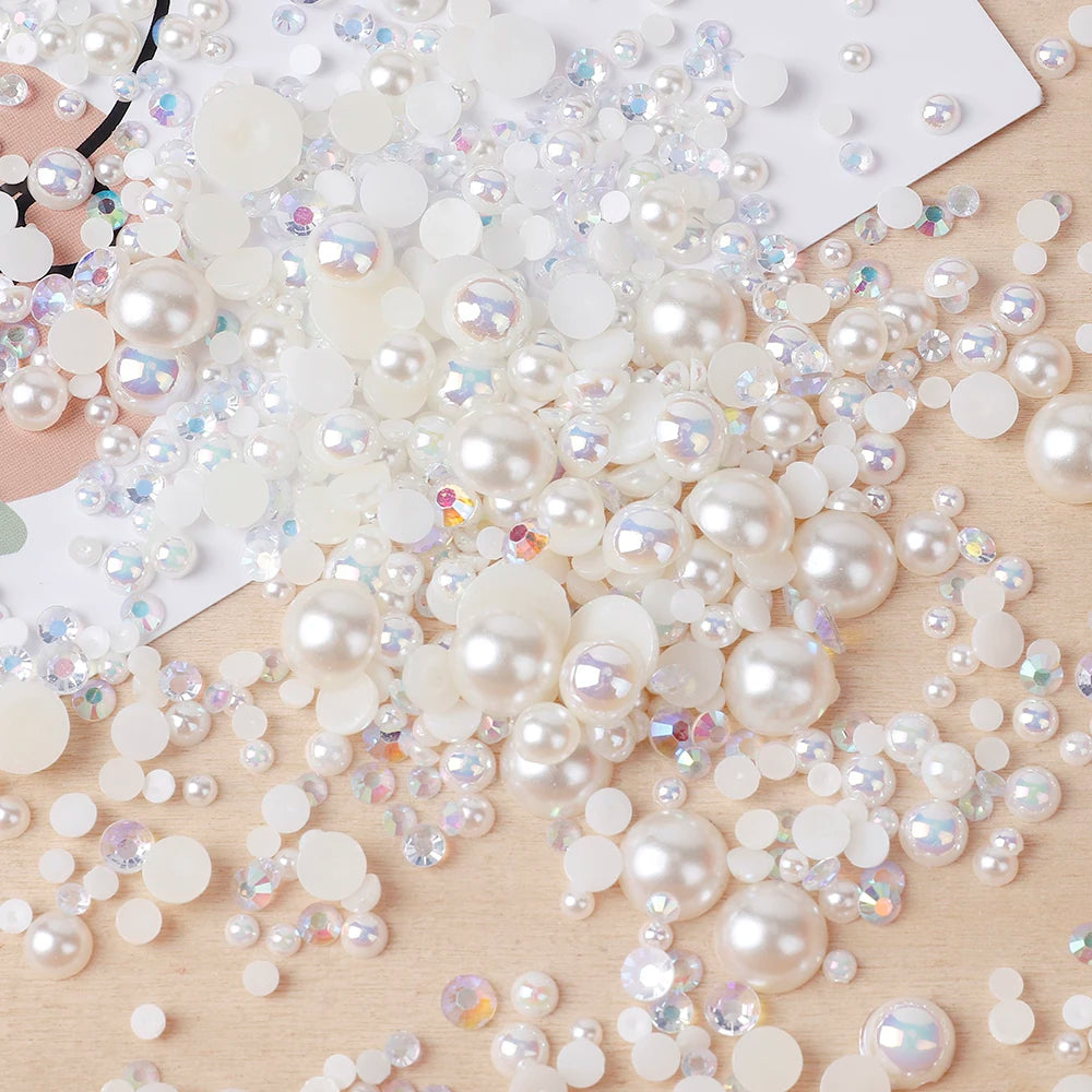 A scatter of mixed resin rhinestone pearls with an AB finish in various sizes and colors on a wooden surface.