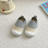 A pair of light gray and white breathable anti-slip baby first walker shoes resting on a white surface next to a calendar.