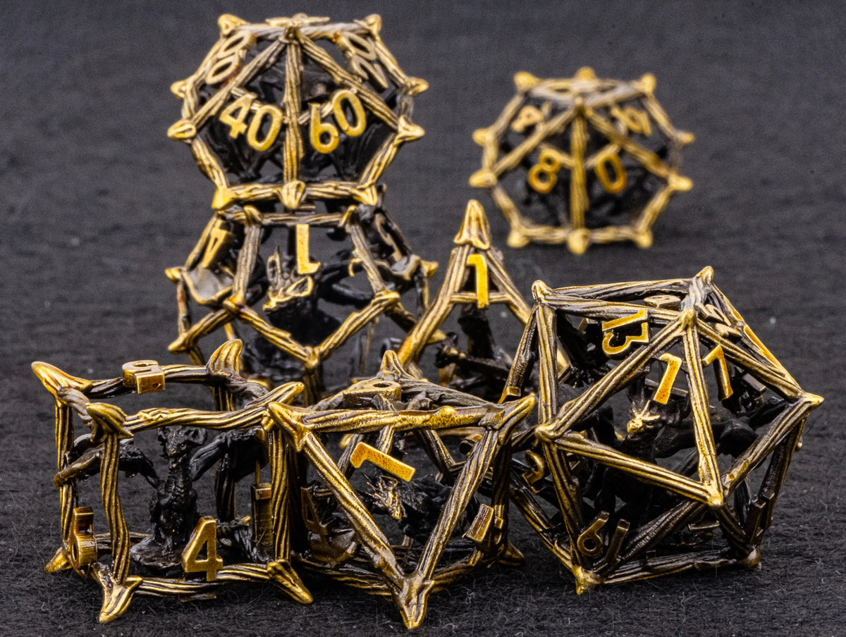 A set of black metal dice shaped like dragons, featuring gold accents, arranged on a dark surface.