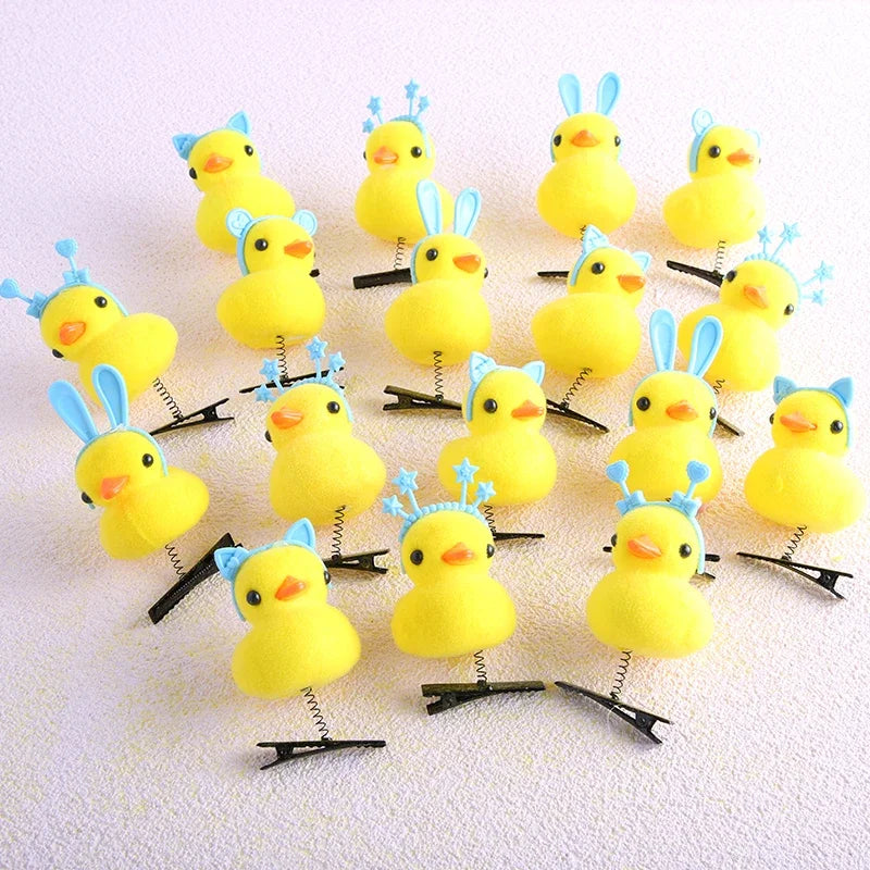 A collection of yellow duck plush hair clips with blue accents arranged on a white background.