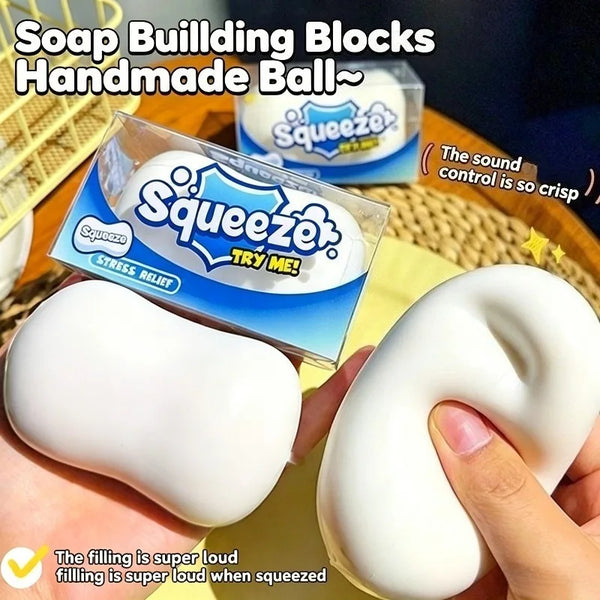 A hand squeezes a white squishy stress ball inside its packaging.