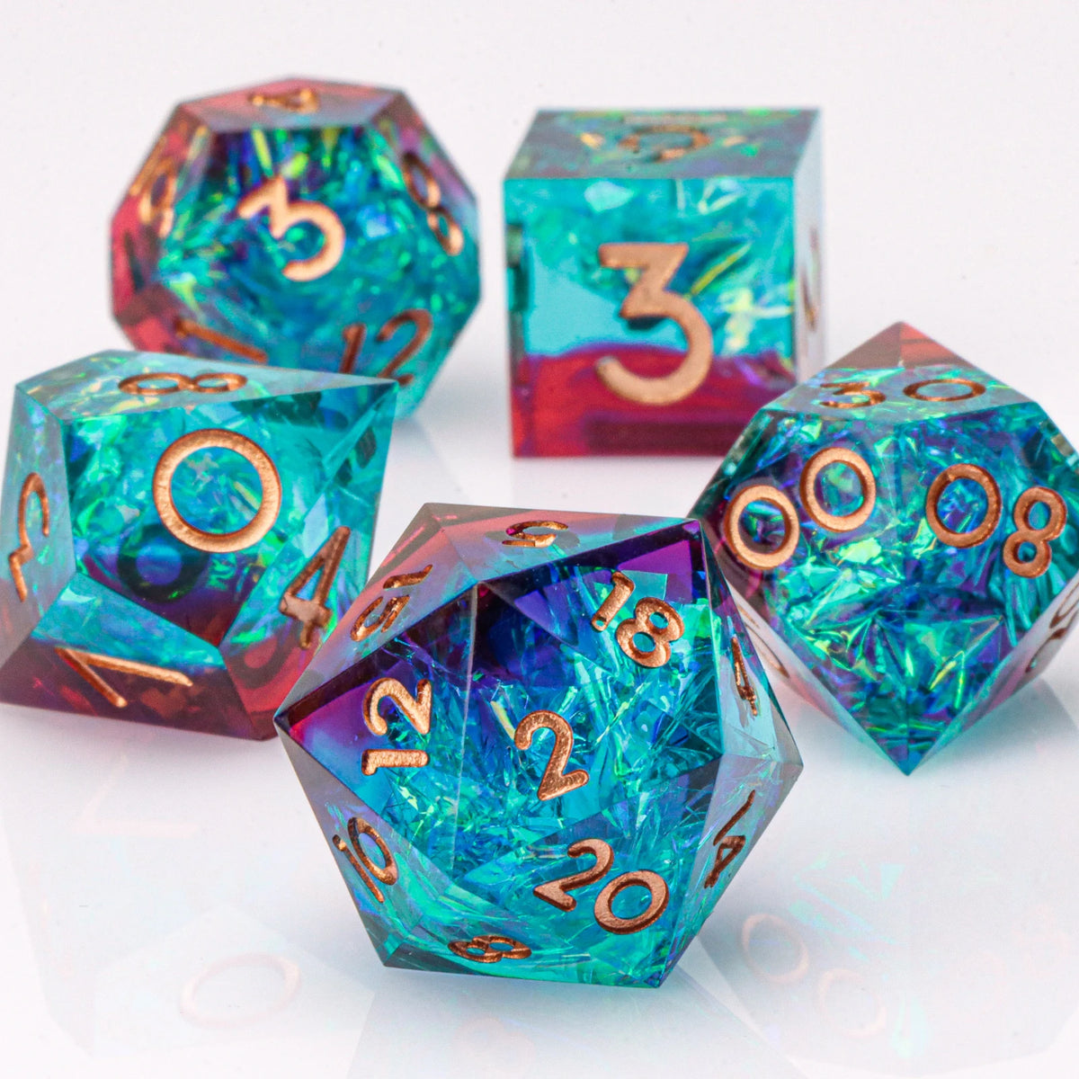 A set of handmade resin polyhedral dice in various colors and shapes resting on a white surface.
