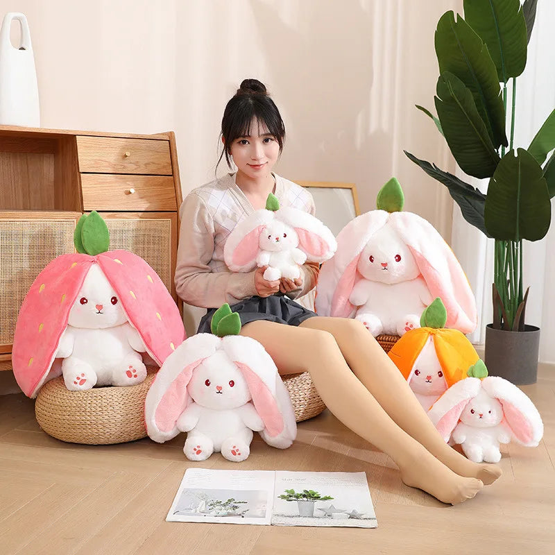A collection of pink and white fruit bunny plush toys arranged on a wooden floor next to an open book.