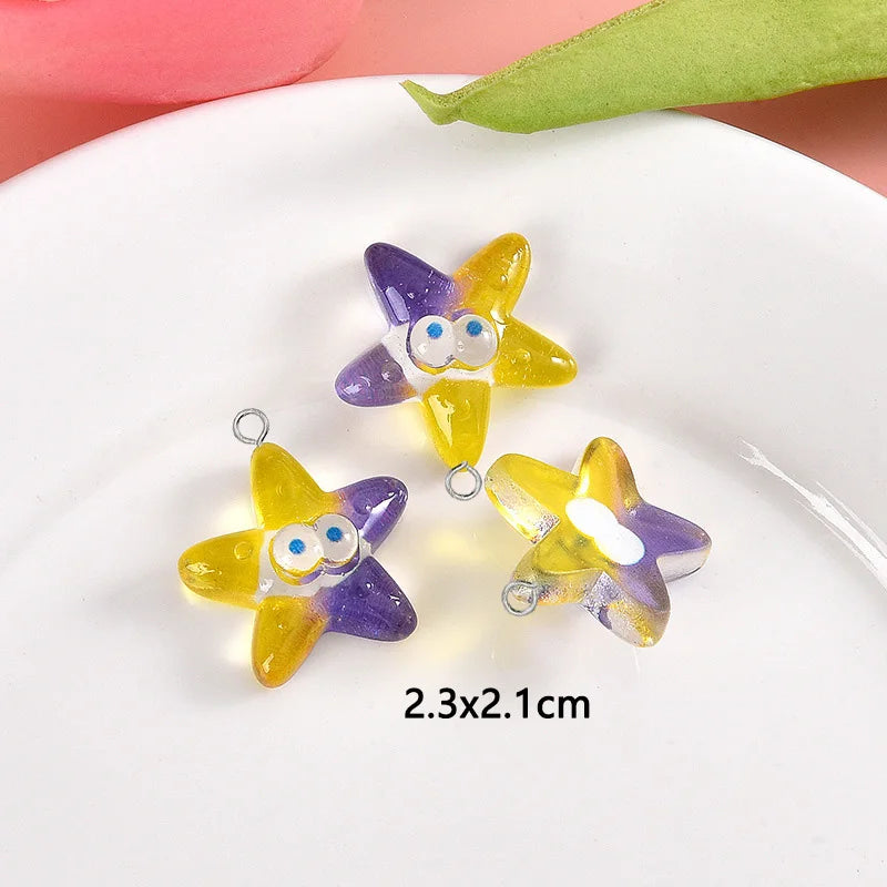 Yellow and purple starfish resin charms for jewelry making displayed on a white plate.