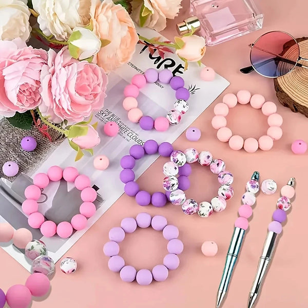 A collection of pink and purple silicone floral beads for DIY jewelry making arranged on a light pink background.