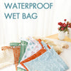 A set of reusable waterproof baby wet bags in various patterns, including orange, green, and light blue, displayed on a white