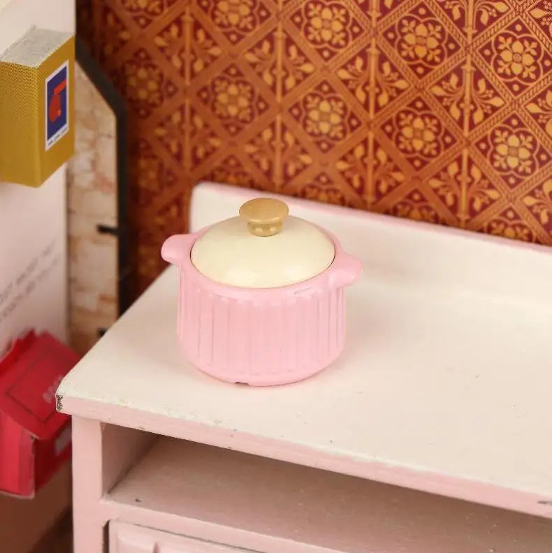 A pink miniature copper soup pot with a lid displayed on a white shelf against a patterned background.