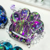 A cluster of iridescent purple and green squishy fidget toys shaped like cat paws.