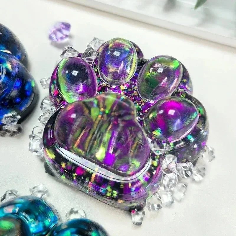A cluster of iridescent purple and green squishy fidget toys shaped like cat paws.