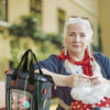A woman holds a canvas knitting tote bag with yarn storage and organizer pockets.