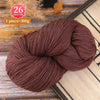 A ball of dark brown premium alpaca blend yarn is shown on a wooden surface.