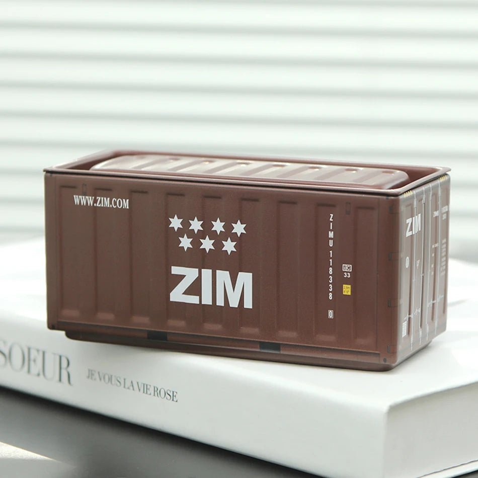 A brown miniature industrial iron storage box with a lid is displayed on a white book.