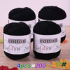 Four skeins of black cotton knitting yarn for crochet and handmade projects displayed on a wooden surface.