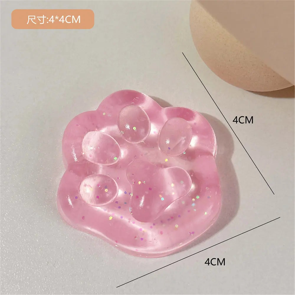 A pink squishy toy shaped like a cat paw, featuring small glitter particles.