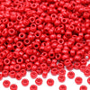 A close-up view of small, round red pony beads scattered on a white background.