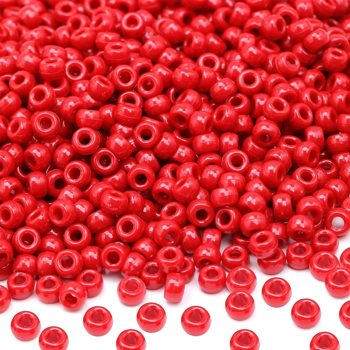 A close-up view of small, round red pony beads scattered on a white background.