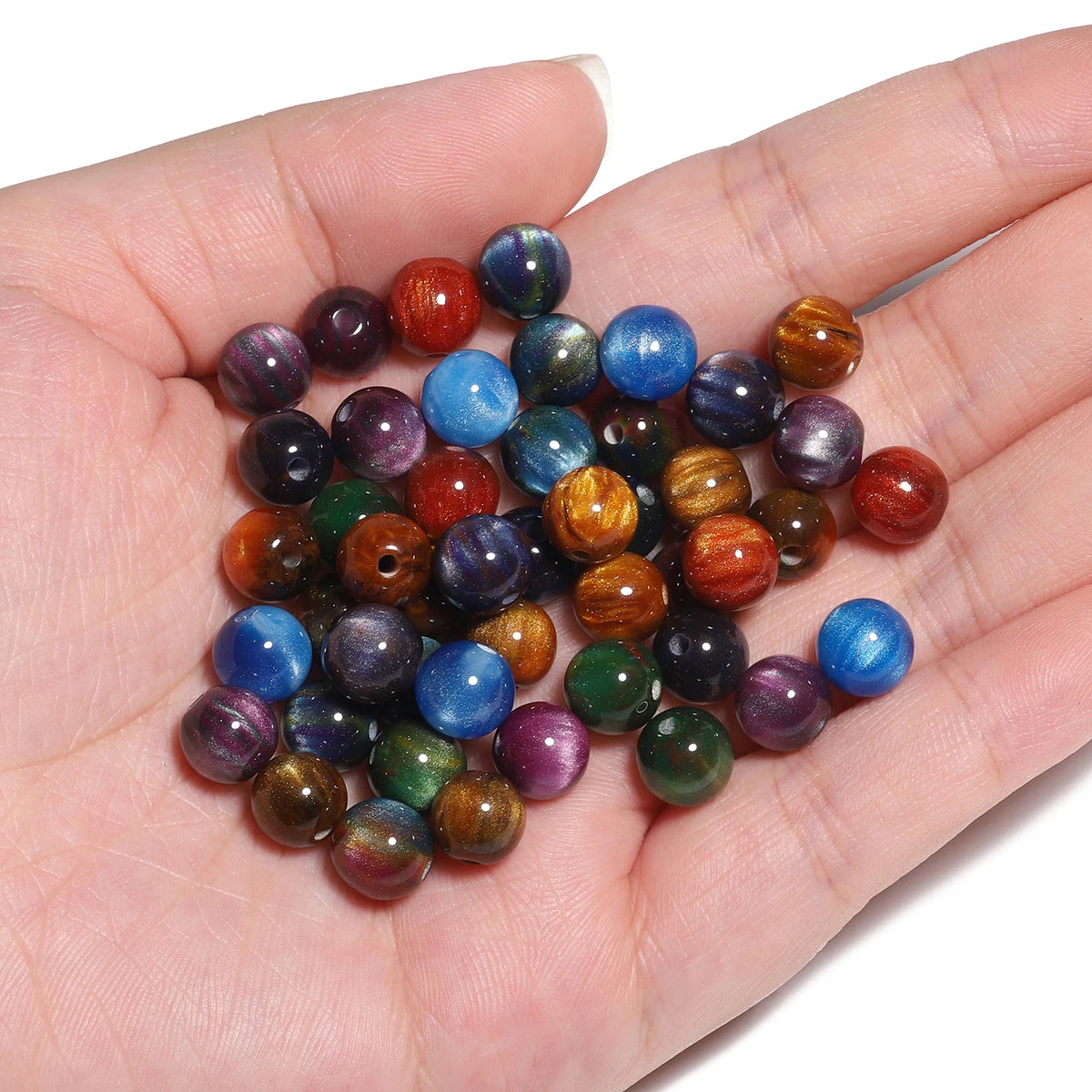 A hand holds a set of 50 vibrant tiger eye resin beads in various colors for jewelry making.