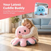A young girl is hugging a pink and blue double-sided flip octopus plush toy on a wooden floor.